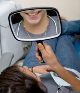 image of a dental patient looking at her teeth in the mirror
