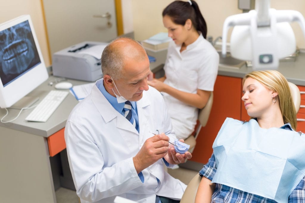 patient at dentist in chair while dentist is explaining procedure