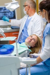 dental patient in exam area with hygienist and dentist